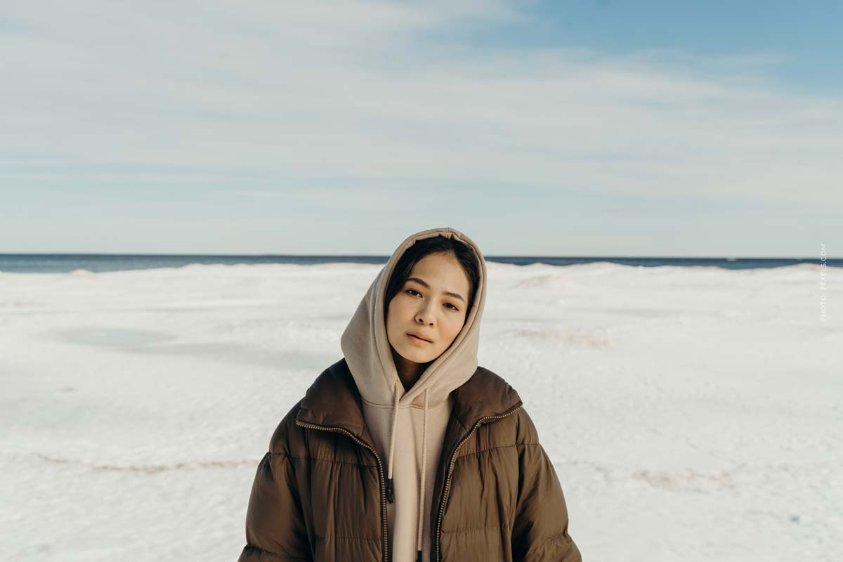 canada-goose-winter-jacket-brown-snow-white-woman-standing-in-snow-desert-blue-sky-clouds