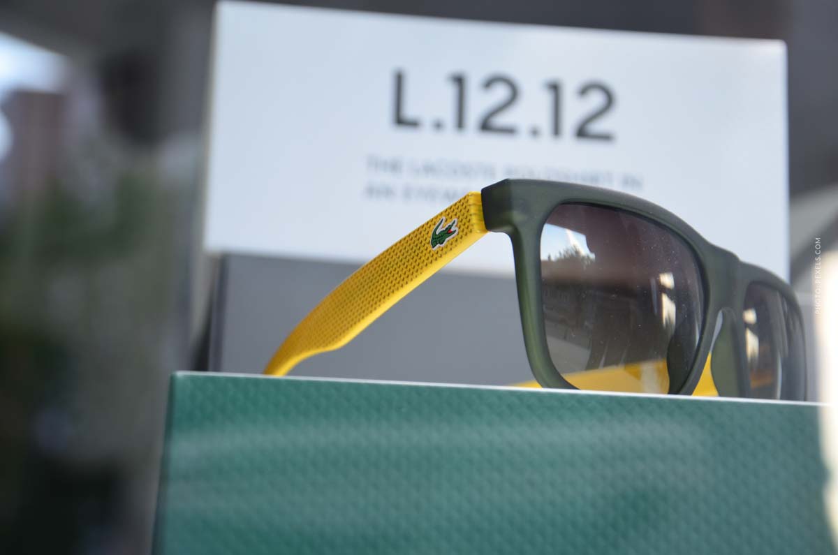 lacoste-sunglasses-yellow-green-presented-on-a-green-pillar