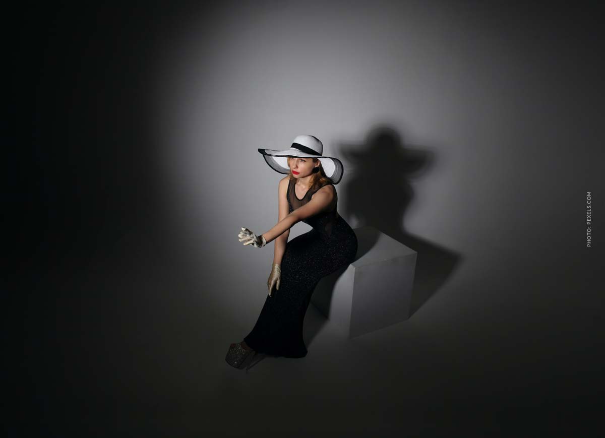 lanvin-designer-fashion-brand-dark-room-with-woman-in-black-dress-and-white-hat-in-the-middle